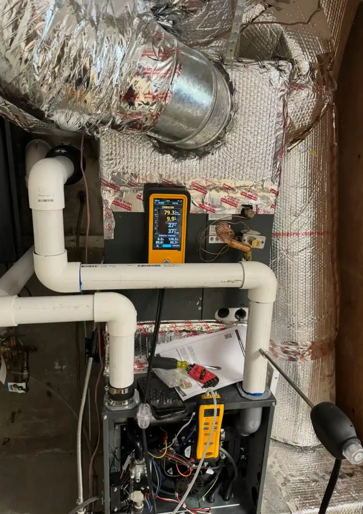 Sealed ductwork intertwined with tubes of a complex heating system.