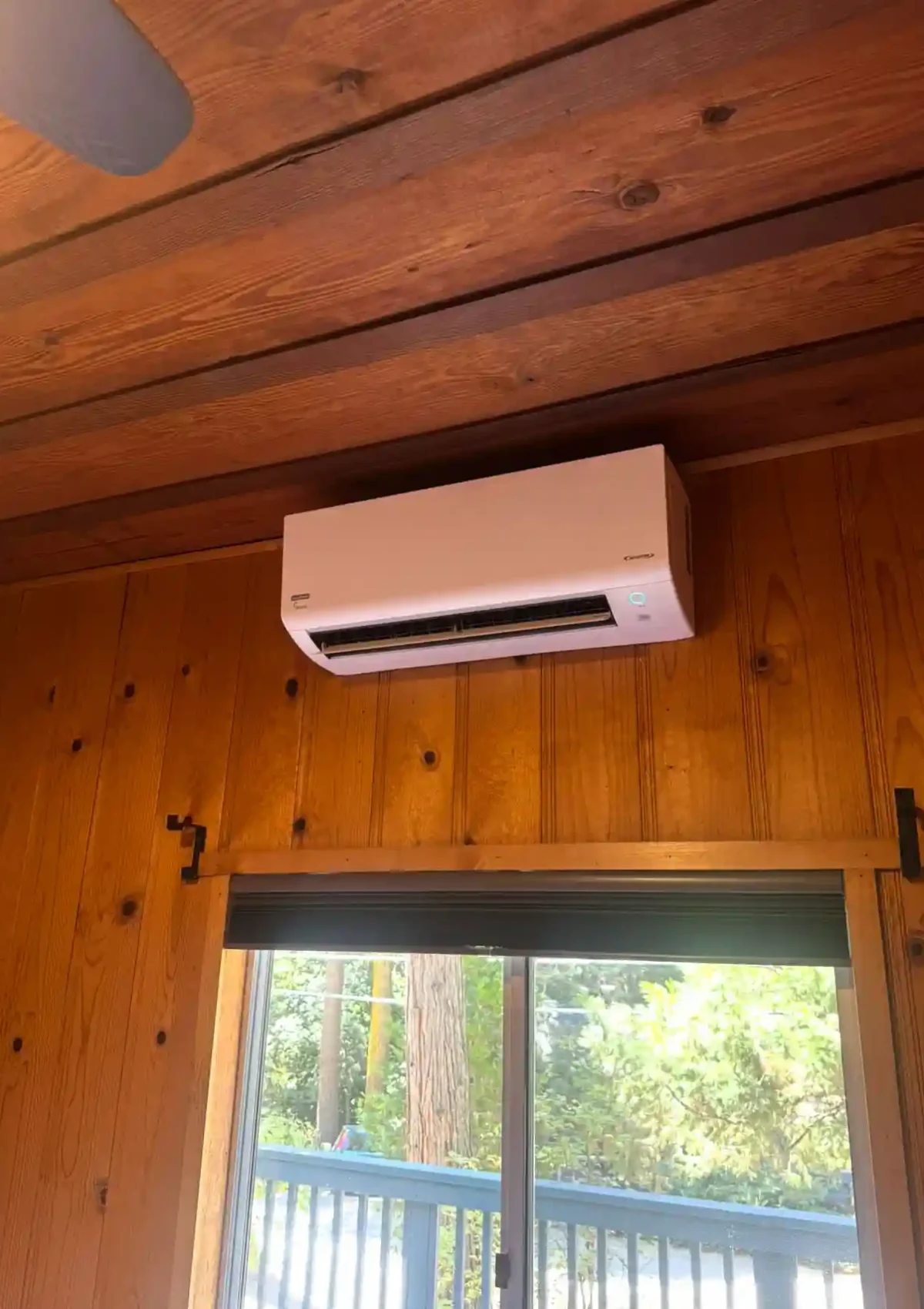 A single air conditioning unit mounted on a wall lined with wooden planks.
