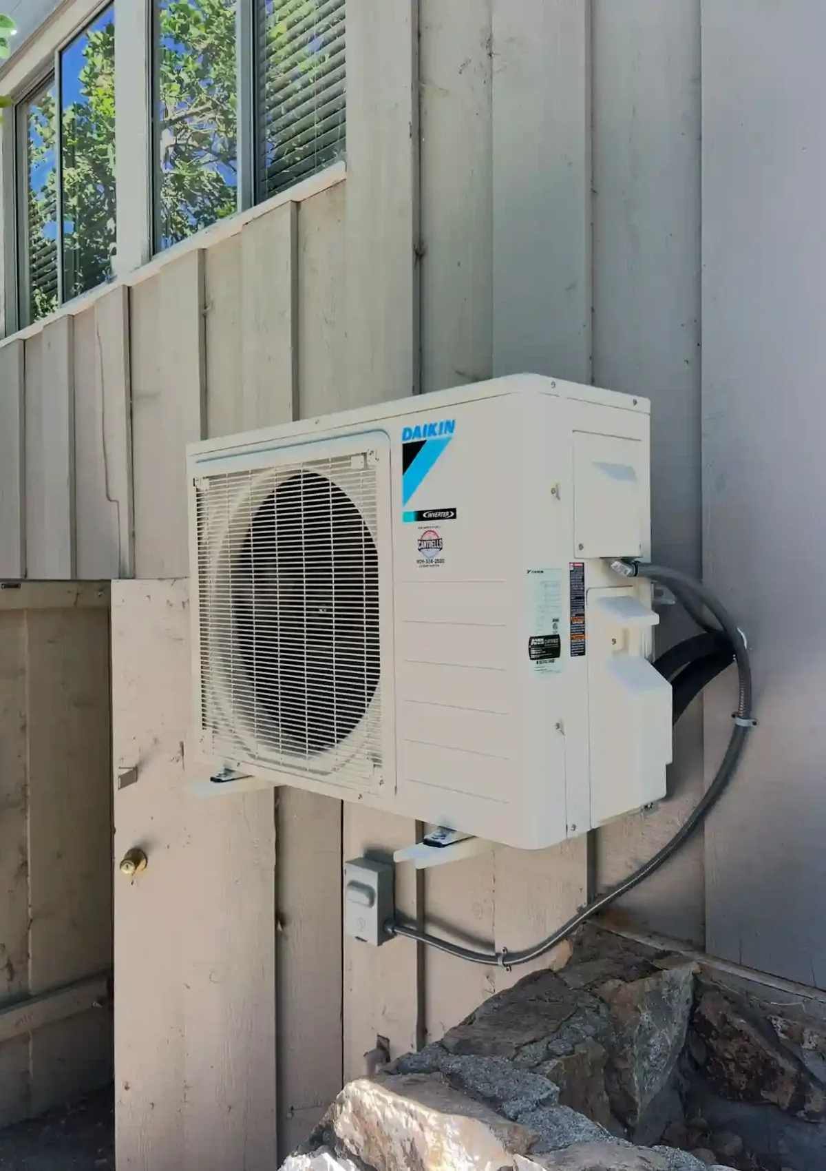 A single mini split air conditioning unit mounted on the siding of the outside walls of a home.